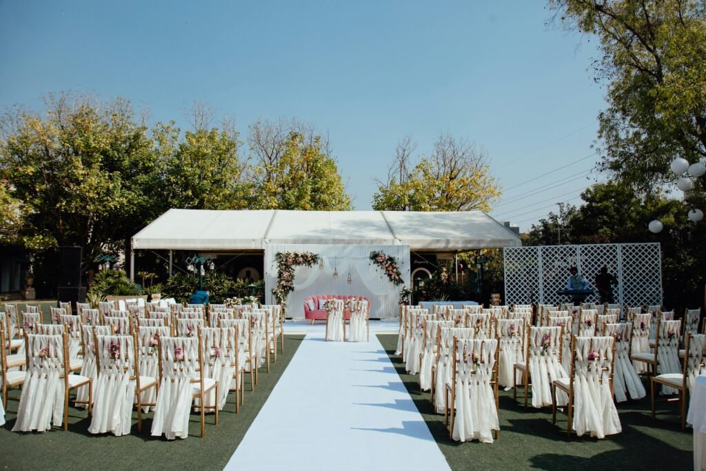 Elegant outdoor wedding setup with decorated chairs and floral arrangements under a clear blue sky.