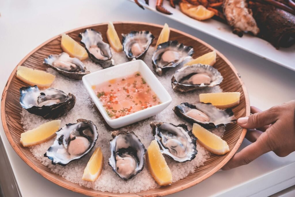 Delicious seafood platter featuring fresh oysters, lemon wedges, and a tangy dipping sauce.