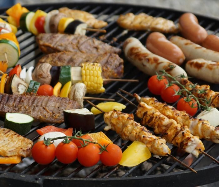 A vibrant assortment of grilled meats, sausages, and vegetables on a barbecue grill.