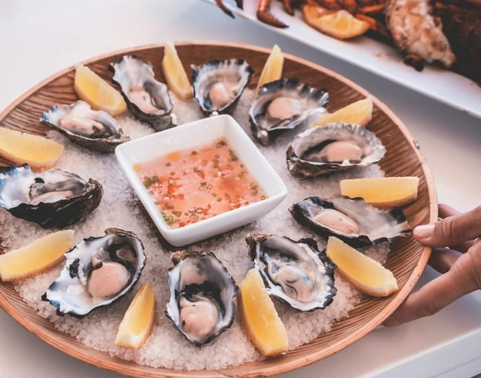 Delicious seafood platter featuring fresh oysters, lemon wedges, and a tangy dipping sauce.